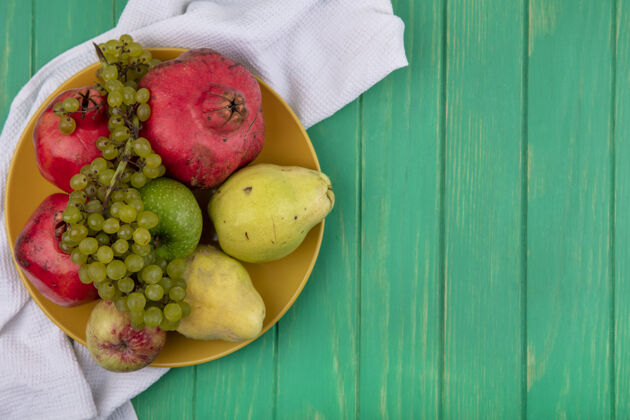 盘子顶视图复制空间石榴与梨苹果和葡萄的盘子上的绿色墙壁苹果有机石榴