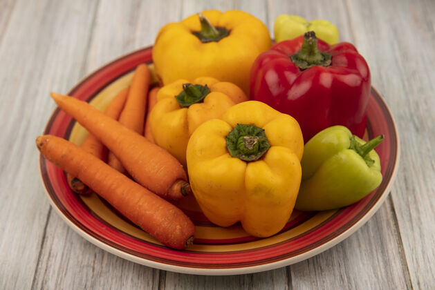 美味顶视图新鲜五颜六色的甜椒与胡萝卜在一个灰色的木制表面盘木头胡椒烹饪