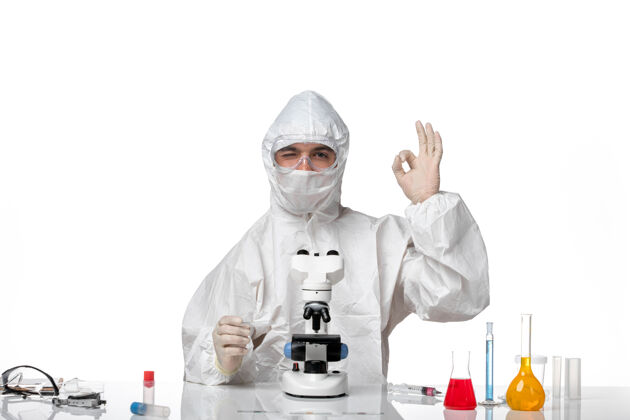 外套正面图：男医生穿着防护服 戴着面罩 用显微镜在空白处摆姿势专业男医生套装