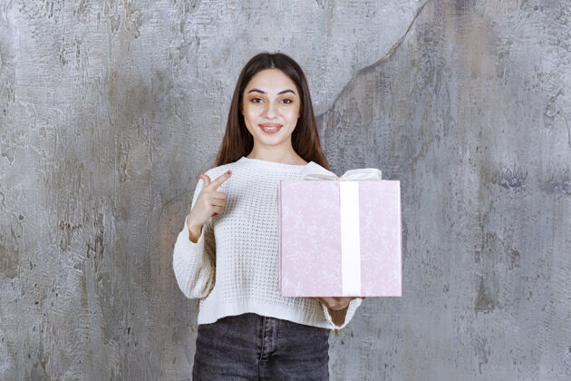 服装女孩手里拿着一个用白丝带包着的紫色礼盒奖励年轻人工人