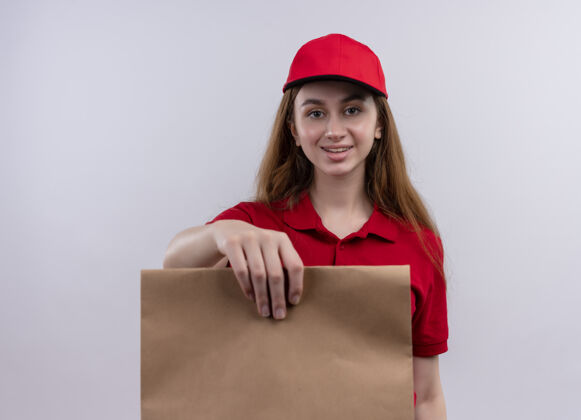 女人身着红色制服 面带微笑的年轻送货员在孤零零的白墙上伸出纸袋年轻微笑女孩