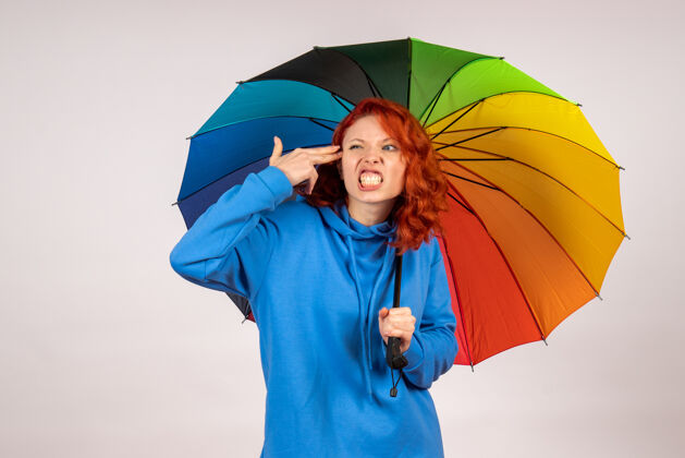 天气白色墙壁上带着彩色雨伞的年轻女性的正视图伞阳伞五颜六色