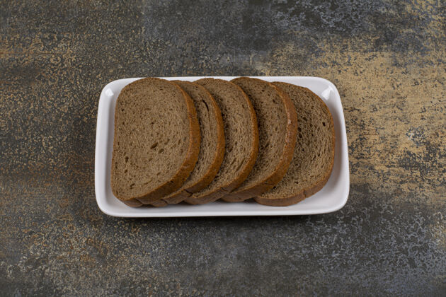 美味黑黑面包片放在白色的方形盘子里新鲜谷类面包