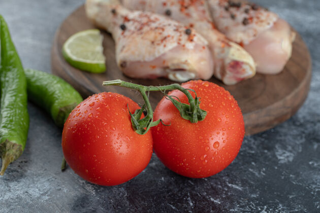 鸡新鲜的有机西红柿和胡椒配生鸡腿的特写照片鸡腿食物生的