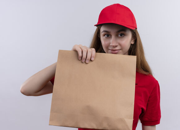 送货穿着红色制服的年轻送货女孩在孤零零的白墙上展示纸袋女孩女人包