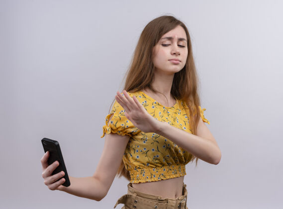 不愉快孤零零的白墙上 一个拿着手机 用手指着手机的年轻女孩指着女人年轻