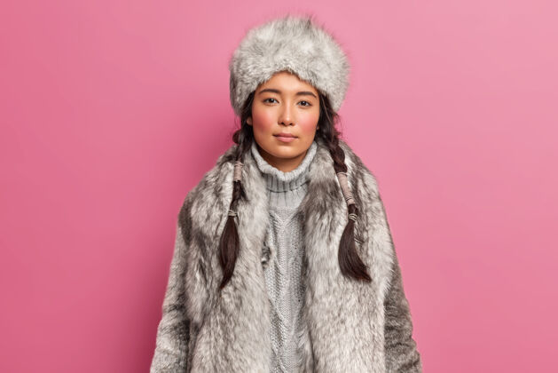 外表北极沃曼的肖像 留着两条辫子 适合寒冷气候的裙子 穿着灰色皮毛外套 戴着隔离在粉色墙壁上的帽子脸帽子女人