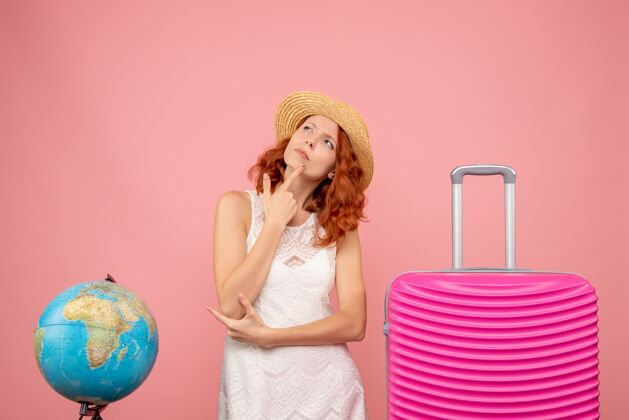 旅行年轻的女性游客与粉红色的袋子思考粉红色墙上的正面视图肖像航行人