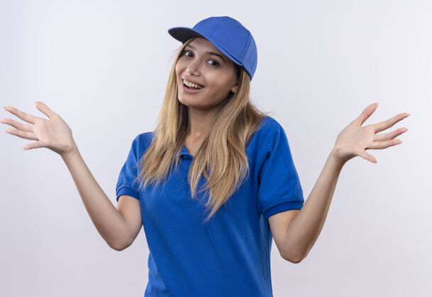 微笑微笑着的年轻送货员身穿蓝色制服 戴着帽子 双手分开放在白色墙壁上 留有复印空间手穿蔓延