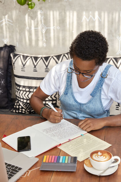 坐垫非裔美国学生做翻译练习 在笔记本上重写句子眼镜坐着开发
