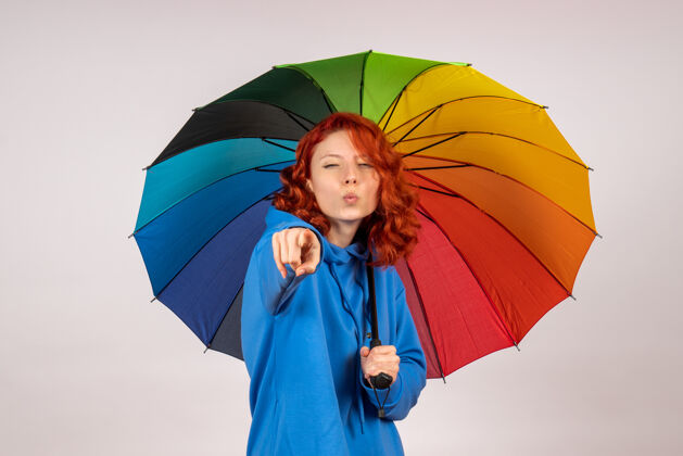 人白色墙壁上带着彩色雨伞的年轻女性的正视图阳伞年轻女性女人