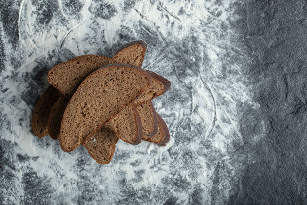 刀面粉背景上切片棕色面包的俯视图选择性聚焦烘焙面粉