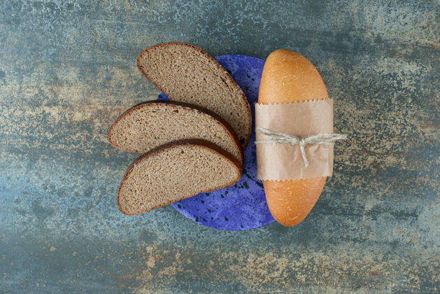 棕色迷你白面包和新鲜的棕色面包片放在蓝色盘子里烘焙营养美味