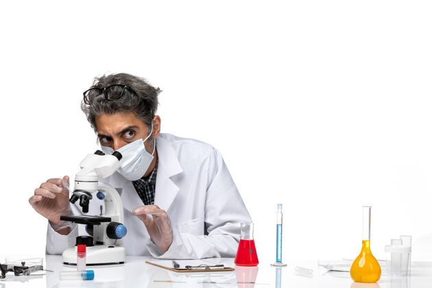 临床前视图穿着白色医疗服的中年科学家正在尝试使用显微镜技师化学专业