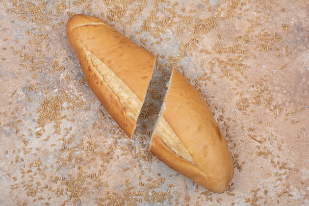 新鲜半切小麦面包和大麦在大理石表面面包食品一半