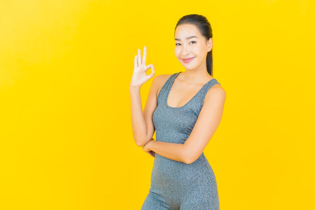 人在黄色的墙上 描绘一位穿着运动服准备锻炼的美丽亚洲年轻女子体重身体脸