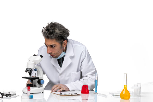 化学穿着白色医疗服的中年科学家使用显微镜的正视图科学正面专业