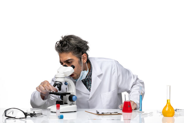 实验室外套穿着白色医疗服的中年科学家使用显微镜的正视图实验病毒实验室