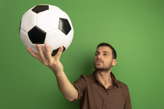 球自信的年轻白种人把足球伸向镜头 在绿色的背景下孤立地看着它伸展年轻足球