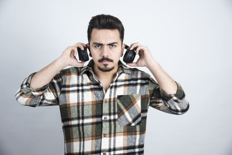 男人戴着耳机的帅哥站在白墙上看的照片享受收音机男人