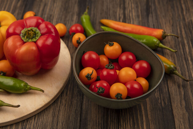 厨房木制厨房板上美味的辣椒和木制墙上碗上的樱桃西红柿的俯视图蔬菜木材碗