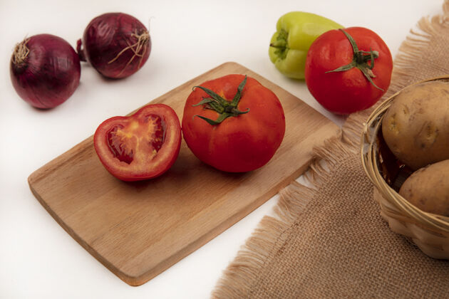 农业顶视图：红色的西红柿放在木制的厨房板上 新鲜的土豆放在桶上 红色的洋葱和绿色的胡椒被隔离在白色的墙上木材厨房洋葱