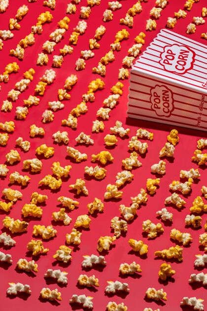 玉米垂直高角度拍摄的爆米花纸杯和爆米花散落在一个红色的表面营养美味音乐会