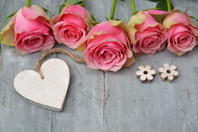 心美丽的粉红色玫瑰 木质的心形 木质表面开着小花芽花木头