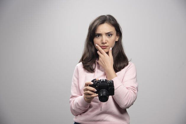女人女摄影师拿着相机思考摄影师女士肖像