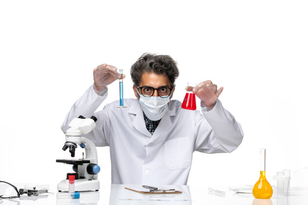 科学正面图穿着特殊套装的中年科学家坐着拿着装有解决方案的烧瓶人面具实验室