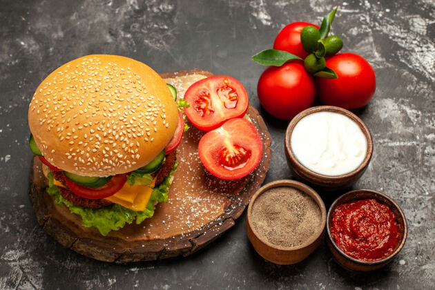 可食用水果前视图芝士肉汉堡和番茄在灰色的表面面包薯条三明治肉薯条奶酪午餐
