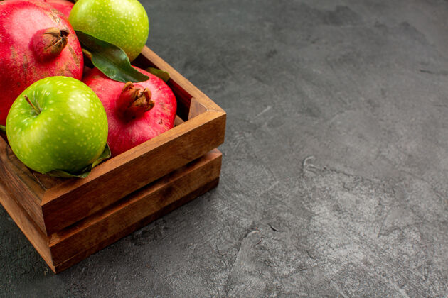 吃苹果正面是新鲜的红石榴和黑地板上的青苹果成熟的水果色柑橘苹果前