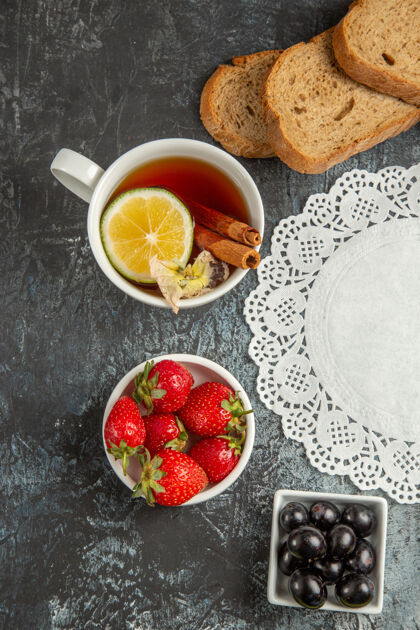 盘子俯瞰一杯茶 在黑暗的表面上放橄榄和水果早餐晚餐草莓小吃