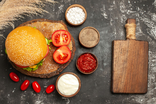 食物顶视图奶酪肉汉堡与调味品在黑暗的表面面包三明治快餐盘子快餐柑橘