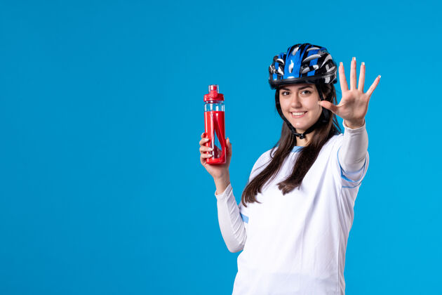 人前视图穿着运动服的年轻女性 蓝色墙上戴着头盔人年轻女性视图