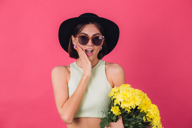成人时尚的女人戴着帽子和墨镜 捧着一大束黄紫苑 春意盎然 兴奋惊艳的情绪张口孤立的空间粉彩祝贺夏天