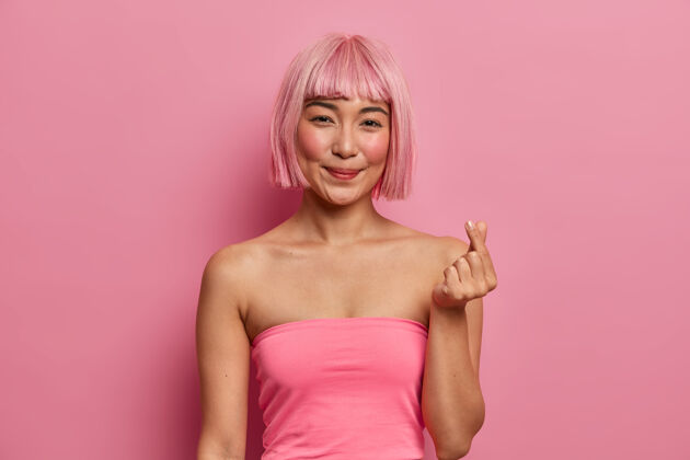 积极美丽微笑的亚洲女士 bob发型 表达爱意 用手指做手势 穿玫瑰色上衣亚洲人手指高兴