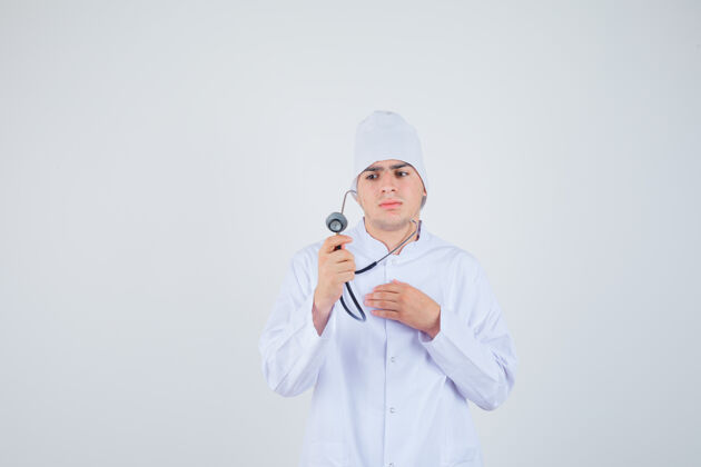 表情医生 一个穿着制服的男孩 手持听诊器 假装在检查心跳 表情严肃 正视图而检查年轻