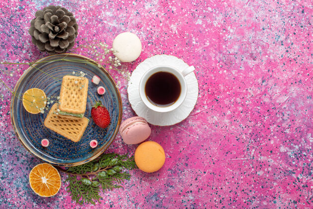 水疗俯瞰美味的华夫饼和法国马卡龙 粉色表面上有茶杯子食物麦卡龙