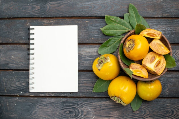 笔记木桌上的柿子新鲜甜美 果实成熟醇厚柑橘健康木头
