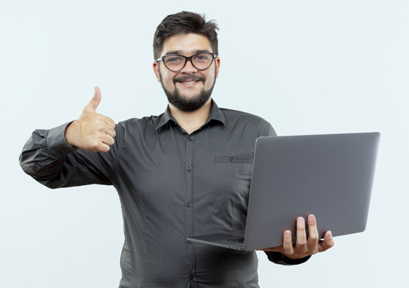 拇指面带微笑的年轻商人戴着眼镜举着笔记本电脑 他的大拇指孤立地站在白色的地板上眼镜手势男人