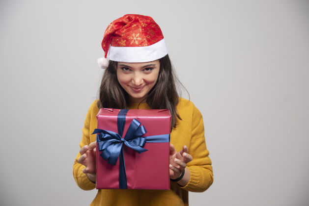 模型戴着圣诞帽拿着礼品盒的快乐女人年轻肖像女士