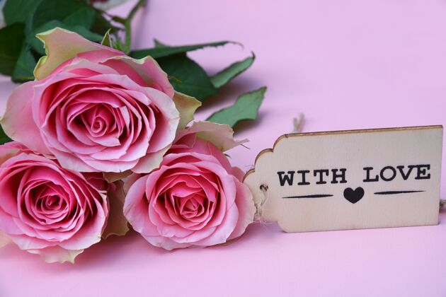 开花粉红色背景下的木装饰旁边的粉红色玫瑰特写图片花自然花蕾