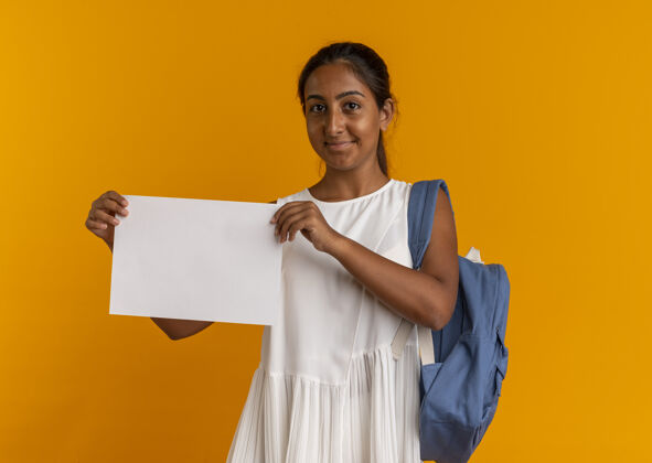 请高兴的年轻女学生戴着背袋拿着橘黄色的纸年轻背纸