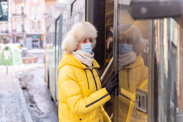 漂亮一个微笑的年轻女人在冬天走进公共汽车公共汽车年轻女孩