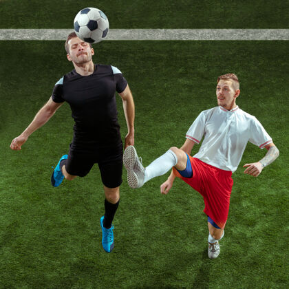 成人足球运动员在绿草背景上抢球向前采取人