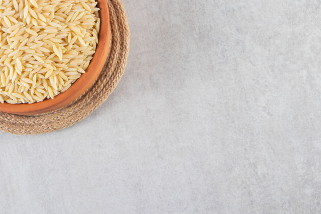 农作物把装满生米的泥碗放在石桌上大米烹饪未煮