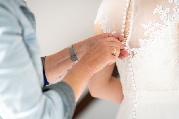 年轻一个男人帮她妻子穿婚纱的特写镜头夫妇女性衣服