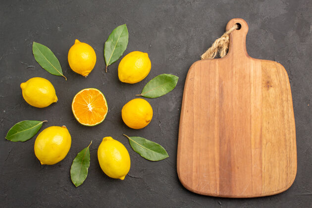 柠檬顶视图新鲜的酸柠檬衬在一张深色的桌子上 橙黄色的柑橘类水果酸橙柑橘砧板