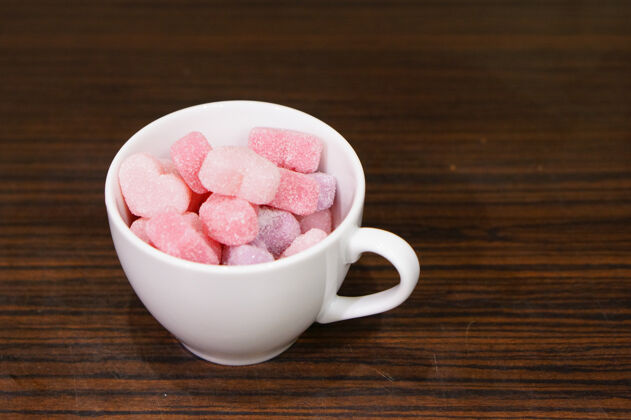 粉色高角度拍摄一个装满果冻糖的杯子心形木头形状